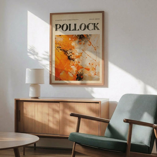 May include: Abstract expressionist poster featuring vibrant orange, white and black paint splatters and gestural brushstrokes, displayed in thin wooden frame above mid-century modern credenza with white ceramic table lamp. Sage green upholstered armchair with wooden frame sits nearby on hardwood floor. Dramatic sunlight creates angular shadows across white wall, highlighting the artwork's dynamic composition and energetic paint application.