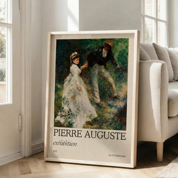 May include: Framed exhibition poster featuring an impressionist painting of a woman in a flowing white dress with blue ribbons and a man in light clothing walking together through a lush green garden or wooded path. The artwork shows loose brushstrokes in greens, blues, and earth tones. Text reads "PIERRE AUGUSTE exhibition 1870 La Promenade" in serif font below the image. The poster leans against a beige sofa in a bright room with white walls and large windows.