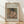 May include: Framed art print leaning against white wall on light wood floor. Wooden frame contains reproduction of Impressionist painting showing woman in dark feathered hat and pink dress drinking from small cup, rendered in soft earth tones. Text above reads "Pierre Auguste Renoir painting" and below "cup of chocolate" on cream textured background.