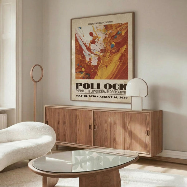 May include: Abstract art exhibition poster with warm orange, red and yellow paint splashes displayed above wooden sideboard in modern living room. White curved chair and glass coffee table visible. Poster features bold "POLLOCK" text and exhibition dates, shown in thin frame against neutral wall.
