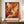 May include: Abstract expressionist poster with dynamic orange, red, black and white paint splatters and brushstrokes in brown wooden frame, displayed on wooden credenza beside white ceramic vase and stacked books against cream paneled wall in modern interior setting.