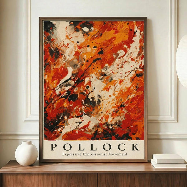 May include: Abstract expressionist poster with dynamic orange, red, black and white paint splatters and brushstrokes in brown wooden frame, displayed on wooden credenza beside white ceramic vase and stacked books against cream paneled wall in modern interior setting.