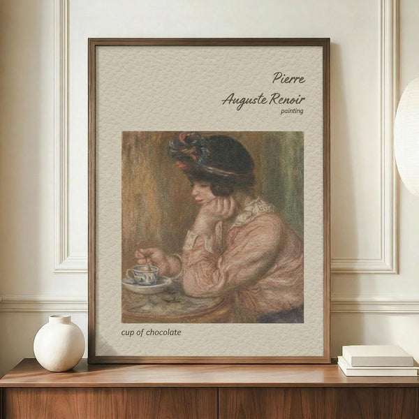 May include: Framed vintage art print showing woman in dark hat and pink dress drinking from teacup, displayed on wooden sideboard next to white ceramic vase and stacked books against cream walls with white trim molding