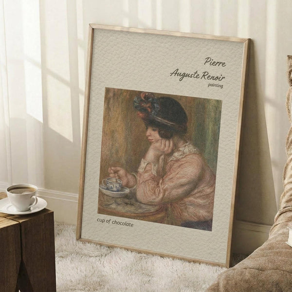 May include: Framed Renoir reproduction showing woman in pink dress and dark feathered hat holding teacup, leaning on hand in contemplative pose. Warm earth tones with impressionist brushwork. Light wooden frame with cream matting displays "Pierre Auguste Renoir painting" and "cup of chocolate" text. Propped against white wall on textured cream rug beside wooden stool with coffee cup, creating cozy room setting with natural window light.