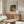 May include: Renoir's "Child with Toys" poster displayed in modern living room with warm wood credenza, white sculptural chair, glass oval coffee table, and contemporary white lamp. The vintage art print shows a woman in rust-colored clothing with blonde child playing with toys, framed in thin wood frame against cream textured mat on white wall.