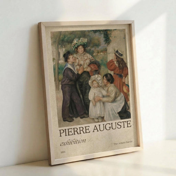 May include: Framed exhibition poster featuring Renoir's 1896 painting of a family group in period clothing - adults and children in white bonnets and dark formal wear against a soft green background. Light wooden frame with cream matting, leaning against white wall. Poster displays "PIERRE AUGUSTE exhibition" text below the artwork with "The Artist's Family" and "1896" details.