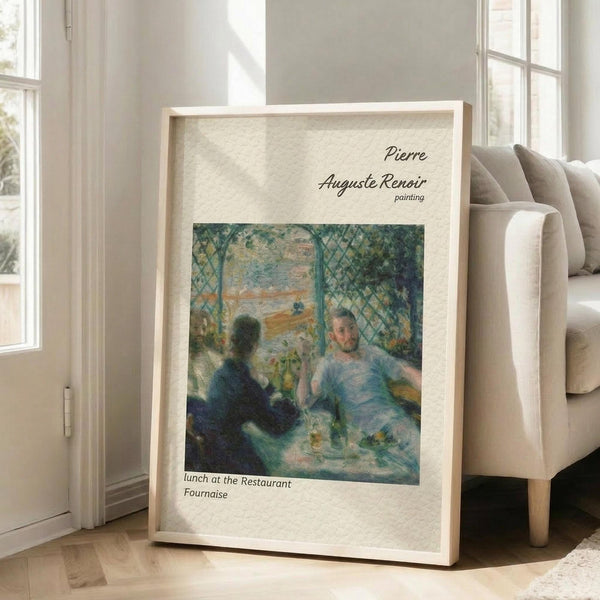 May include: Framed art print of Renoir's impressionist painting showing people dining at a restaurant, displayed in light wood frame against white wall next to beige upholstered chair. The artwork features soft blues and greens with figures seated at a table under latticed canopy. Print has cream colored mat with artist attribution text above and title below the image.