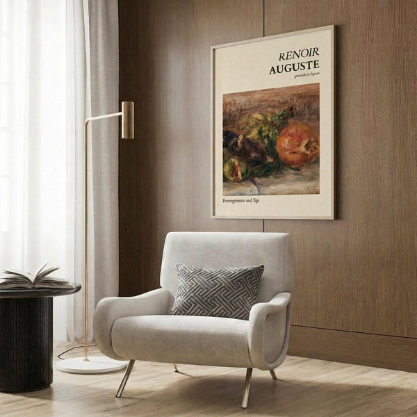 May include: Cream-colored framed art print featuring Renoir's still life painting of pomegranate and figs in warm oranges and greens, displayed on wood-paneled wall above beige upholstered armchair with geometric patterned pillow, brass floor lamp and dark round side table with open book in modern neutral-toned room setting.