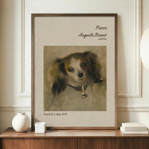 May include: Framed vintage dog portrait print displayed on wooden sideboard next to white ceramic vase and books. The reproduction features a small spaniel-type dog with long ears and collar against muted brown background. Cream matting surrounds the artwork in thin wooden frame. Soft natural lighting illuminates the elegant interior setting with white paneled walls.