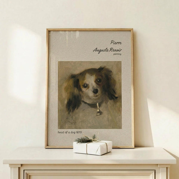 May include: Framed art print of a small dog with brown and white fur and dark ears wearing a collar, displayed on a light wooden console table next to a wrapped white gift box with evergreen sprig. The vintage-style painting reproduction is mounted in a thin wooden frame with cream matting against a soft beige wall.