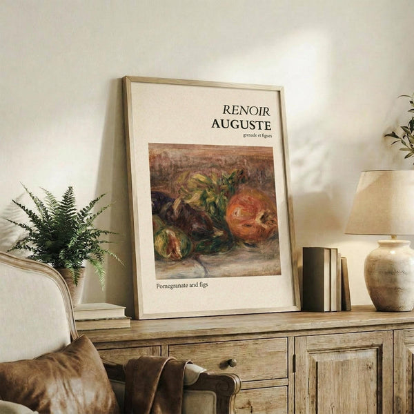 May include: Framed art print featuring a still life painting of pomegranate and figs in warm earthy tones, displayed on a rustic wooden sideboard alongside books, a ceramic vase, and fern plant in a neutral-toned living room setting with cream armchair and throw pillows.