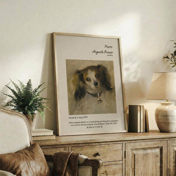 May include: Framed vintage-style dog portrait poster displayed on rustic wooden console table alongside fern plant, ceramic vases, and books. The artwork shows a small spaniel-type dog with long ears and collar in muted brown tones. Light wood frame with white matting against cream wall in cozy living room setting with upholstered chair visible.