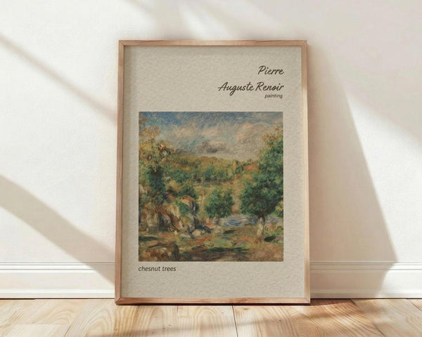 May include: Framed art print of Pierre-Auguste Renoir's impressionist landscape painting featuring lush green chestnut trees, rolling hills, and soft cloudy sky in warm earth tones. The beige matted print sits in a light wood frame against white walls on hardwood floors with natural sunlight casting diagonal shadows across the scene.