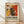May include: Framed abstract art poster with vibrant red, yellow, black and white paint splatters and dynamic brushstrokes in Jackson Pollock style, displayed in light wood frame against white textured wall on natural wood floor with soft window light creating diagonal shadows across the scene.