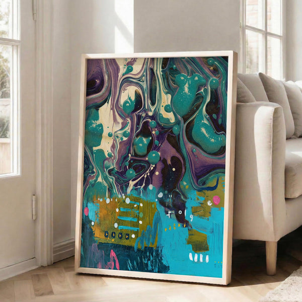 May include: Large framed abstract art print with swirling purple and teal marbled patterns in upper portion, transitioning to bright blue and golden yellow brushstrokes below with scattered white dots and pink accents. Natural wood frame leans against white wall next to beige upholstered chair in bright room with large windows and hardwood floors.