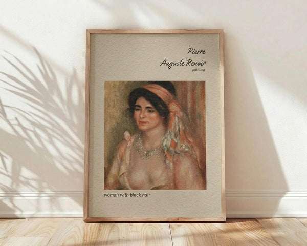 May include: Framed art print displaying a Renoir painting of a woman with dark hair wearing a coral headband and pearl necklace, rendered in soft impressionist brushstrokes with warm peachy tones. The wooden frame sits on light wood flooring against a white textured wall with dramatic palm leaf shadows creating striped patterns across the scene.