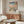 May include: Japanese woodblock print depicting snowy winter landscape with Mount Fuji, bridges over blue water, and bare trees, displayed in thin wooden frame above mid-century modern walnut credenza. White sculptural chair and glass-top coffee table visible in minimalist living room with cream walls and natural lighting.
