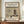 May include: Framed vintage Japanese woodblock print showing snow-covered temple pagoda with figure holding umbrella, displayed on wooden console beside white ceramic vase and books against cream wall with white molding