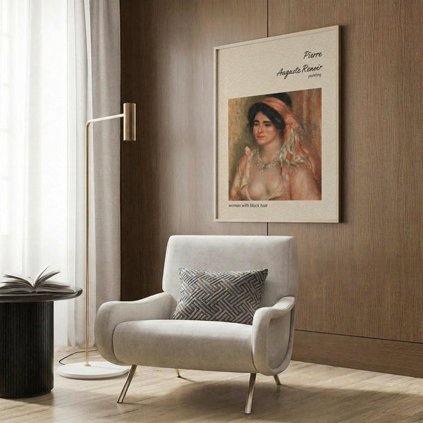 May include: Framed vintage art print featuring a woman with dark hair in soft pink and coral tones, displayed on wood paneled wall above a cream upholstered armchair with geometric patterned pillow. Modern reading corner with brass floor lamp, black side table with open book, and natural lighting from window with white curtains.