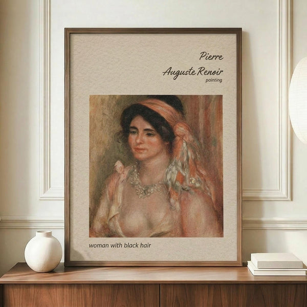 May include: Framed poster print of a Renoir painting featuring a woman with dark hair and flowing fabric in warm peachy tones, displayed on a wooden sideboard next to a cream ceramic vase and white books in an elegant room with cream walls and wainscoting.