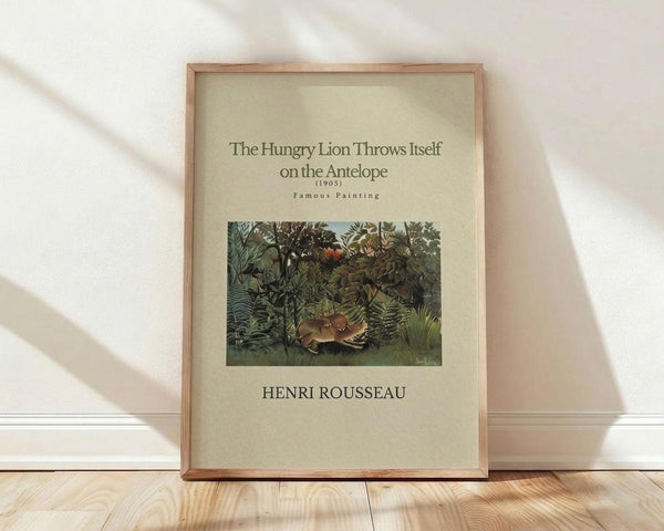May include: Framed art print featuring Henri Rousseau's jungle painting with a lion attacking an antelope among lush green foliage. The poster has cream-colored background with dark text displaying the artwork title, date 1905, "Famous Painting" and artist name. Natural wood frame sits on light wooden floor against white wall with soft natural lighting creating diagonal shadows.