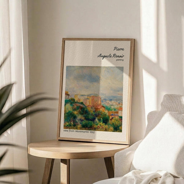 May include: Framed art print displaying an impressionist landscape painting with green foliage, orange and yellow buildings, and blue sky. The poster features "Pierre Auguste Renoir" text and "view from Montmartre 1892" caption. Shown in thin wooden frame on round wooden side table next to cream upholstered chair, with plant shadows on white wall and natural sunlight streaming across the scene.