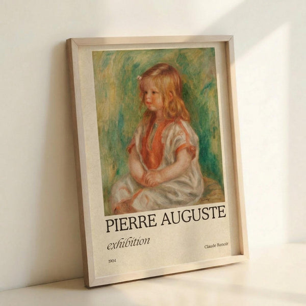 May include: Framed exhibition poster featuring a Renoir painting of a young blonde girl in a white dress with orange vest, seated against green brushstroke background. Poster displays "PIERRE AUGUSTE exhibition" and "Claude Renoir 1904" text below the artwork. Light wood frame sits on white surface against white wall with soft shadows.