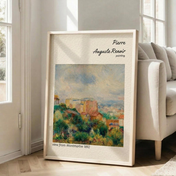 May include: Framed poster print of Pierre-Auguste Renoir's impressionist landscape painting showing colorful Mediterranean buildings and lush green foliage under a cloudy sky. The artwork is displayed in a light wood frame, leaning against white walls near a beige upholstered sofa in a bright, sunlit room with large windows and hardwood floors.