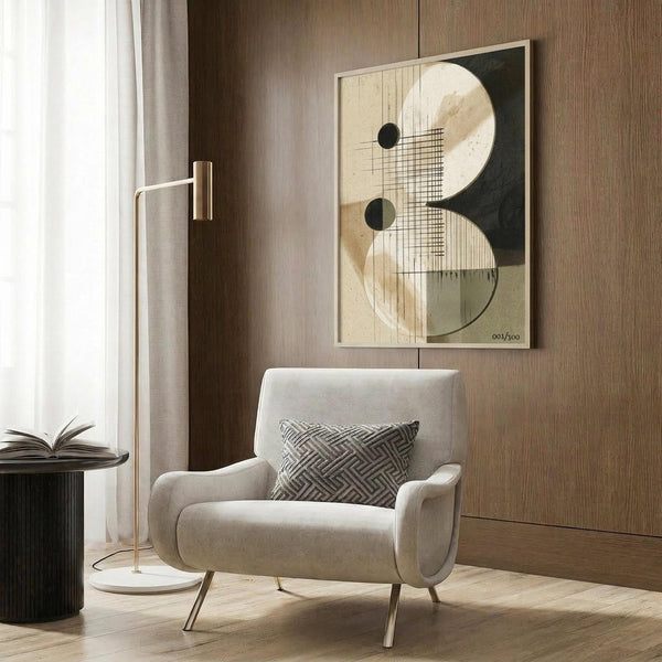May include: A modernist abstract poster with geometric shapes in cream, black, and gold tones displayed on a wood-paneled wall above a beige upholstered armchair with geometric throw pillow. The artwork features overlapping circles, grid patterns, and linear elements in a neutral color palette. Scene includes a brass floor lamp and side table in a contemporary living room setting with natural lighting from sheer curtained windows.