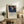 May include: Framed Japanese woodblock print featuring a detailed hawk in flight against deep blue starry sky above snowy landscape, displayed on rustic wooden sideboard alongside fern plant, books, and ceramic vase in neutral-toned living room setting with cream upholstered furniture and warm natural lighting.