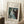 May include: Framed art print featuring Renoir's impressionist painting of a woman in a flowing white dress playing piano, displayed in light wood frame against white wall in cozy room setting with white coffee cup on wooden block, cream textured rug, and soft natural lighting creating window shadows.