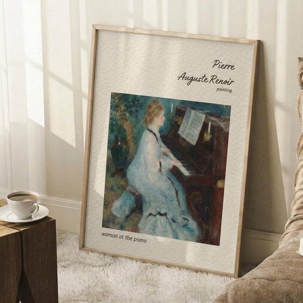 May include: Framed art print featuring Renoir's impressionist painting of a woman in a flowing white dress playing piano, displayed in light wood frame against white wall in cozy room setting with white coffee cup on wooden block, cream textured rug, and soft natural lighting creating window shadows.