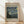 May include: Framed poster print featuring Van Gogh's The Starry Night painting with swirling blue sky, bright yellow stars, and dark cypress tree. Museum-style beige background with black text reading "VAN GOGH" at top, "1889" in corner, and descriptive text below the artwork. Natural wood frame leaning against white wall on light wooden floor with soft sunlight shadows.