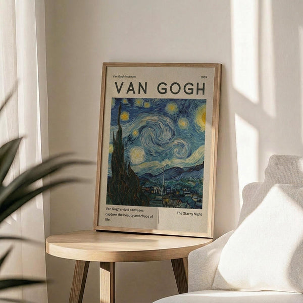May include: Framed Van Gogh Starry Night museum poster in light wood frame, displayed on round wooden side table next to beige upholstered chair. Poster features swirling blue night sky with yellow stars and moon above dark village silhouette. Soft natural lighting creates shadows on neutral wall, with plant leaves visible in corner.