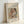 May include: Framed art print leaning against white wall showing Renoir's soft impressionist painting of a woman in earth tones holding a young child. The artwork features warm pastels and loose brushstrokes typical of the artist's style. Text above reads "Pierre Auguste Renoir painting" and below "washerwoman and child." Natural wood frame with light matting, photographed in soft natural lighting.