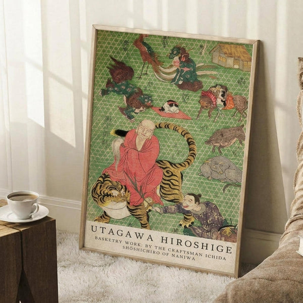 May include: Framed Japanese woodblock print poster leaning against white wall in cozy room setting. Green geometric patterned background features colorful illustrations of animals, figures in traditional robes, and a monk with tiger. Natural wood frame, positioned on white textured rug next to wooden side table with coffee cup. Soft natural lighting creates window shadows on wall.