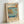 May include: Framed vintage Japanese woodblock print showing a coastal scene with rocky cliffs, blue ocean waters, small boats, and Mount Fuji in the distance. The artwork features traditional ukiyo-e style with muted earth tones and blue hues, displayed in a light wooden frame against a white wall. Japanese text cartouches visible in upper right and lower left corners of the print.