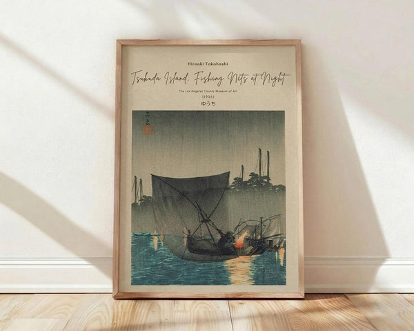 May include: Framed vintage Japanese woodblock print showing fishing boats with large nets at twilight on blue-green water. The artwork features muted earth tones with atmospheric fog or mist, displayed in a natural wood frame against white walls on light wooden flooring with soft window light casting shadows.