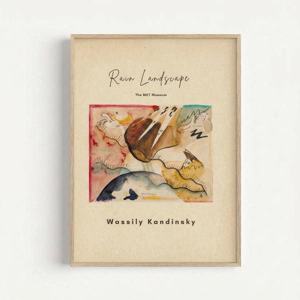 May include: Framed museum poster featuring Kandinsky's abstract watercolor painting with flowing organic shapes in warm browns, yellows, and cool blues and greens, displayed against a light gray wall. The cream-colored mat shows handwritten-style text reading "Rain Landscape," "The MET Museum," and "Wassily Kandinsky" in elegant typography, all contained within a simple light wood frame.