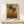 May include: Framed sunflower artwork print displayed on light wood console table against cream wall. The botanical illustration shows three large yellow sunflowers with brown centers and green leaves against blue sky with golden field background. Natural wood frame with white matting. Small wrapped gift box with twine sits beside the frame. Warm, minimalist home decor styling.