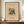 May include: Framed vintage-style art print featuring Wassily Kandinsky's abstract composition with colorful geometric shapes, lines, and forms on cream background. German text at top reads "Lithographie fur die Vierte Bauhausmappe" with "The MET Museum" and artist name below. Brown wooden frame displayed on walnut credenza beside white ceramic vase and stacked books against cream wainscoted wall.
