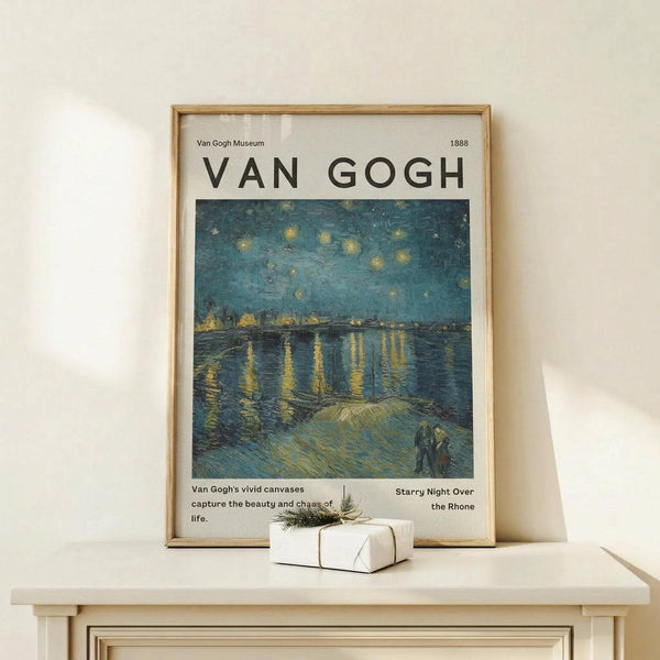 May include: Framed Van Gogh museum poster showing Starry Night Over the Rhone painting with swirling blue night sky, golden stars, and reflections on water. Light wood frame displayed on white wooden console table with small wrapped gift box with natural twine and pine sprig. Clean minimal styling against cream wall with soft natural lighting.