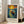 May include: Framed poster with Van Gogh-inspired artwork showing a figure standing in a wooden boat on swirling blue water under a dramatic yellow sun and colorful sky. The print features thick, painterly brushstrokes in blues, oranges, and yellows. Text below reads "Vincent Van Gogh" with a quote about dreaming and painting. The light wood frame leans against a white wall next to a beige sofa in a bright room with large windows.