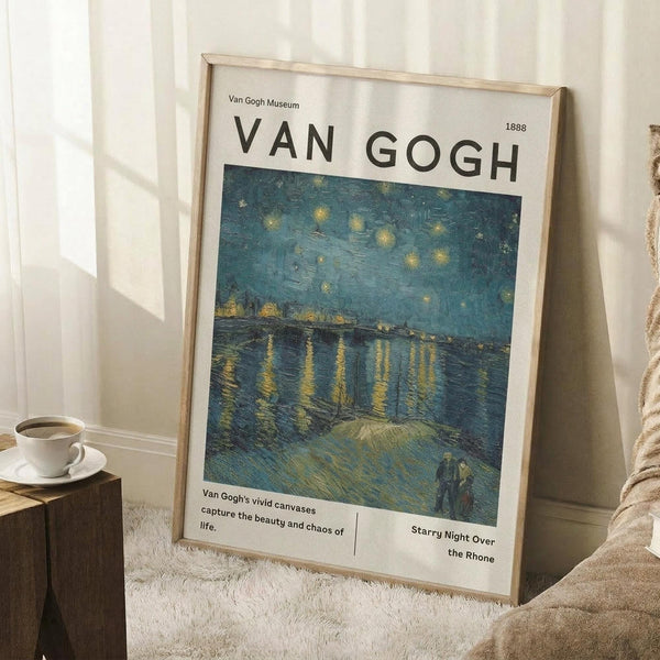 May include: Van Gogh museum-style poster in light wood frame leaning against white wall corner. Shows Starry Night Over the Rhone painting with swirling blue night sky, yellow stars, bridge over water with golden reflections, and two figures on shoreline. White border with black text and 1888 date. Coffee cup on wooden block and beige blanket nearby on textured white rug.