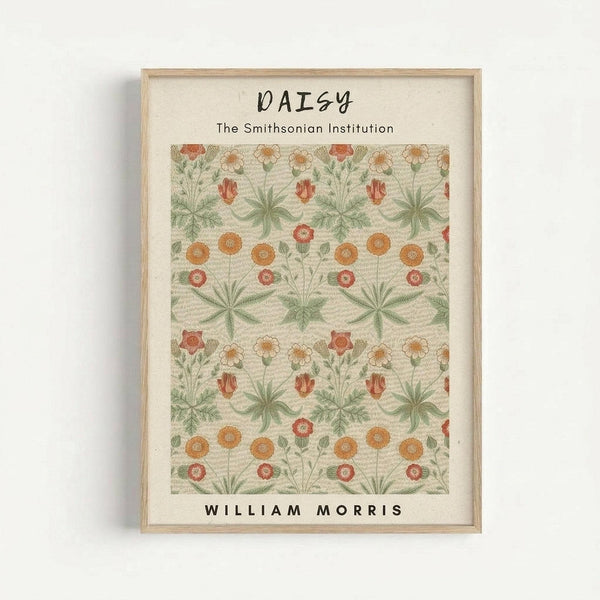 May include: Framed botanical art print featuring William Morris daisy pattern with repeating orange and coral flowers, green foliage, and cream background. The artwork is displayed in a light wood frame against a white wall, showing detailed floral motifs arranged in symmetrical rows with daisies, leaves, and decorative botanical elements in vintage Arts and Crafts style.