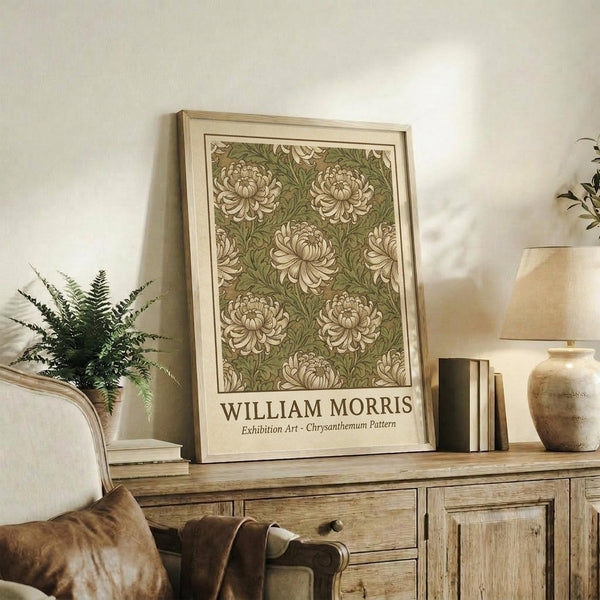May include: Framed botanical art print featuring green and cream chrysanthemum floral pattern displayed on rustic wooden sideboard beside fern plant, ceramic vase, and books in warm neutral living room setting with beige chair and lamp