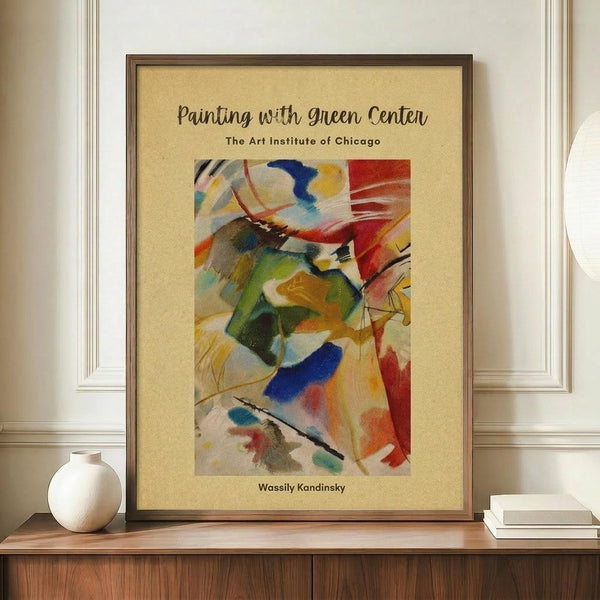 May include: Framed abstract art poster displayed on wooden sideboard next to white ceramic vase and stacked books. The artwork features vibrant swirling brushstrokes in green, blue, red, yellow and orange on cream background. Brown wooden frame complements warm neutral wall setting. Exhibition-style poster format with museum text above and artist name below the colorful abstract composition.