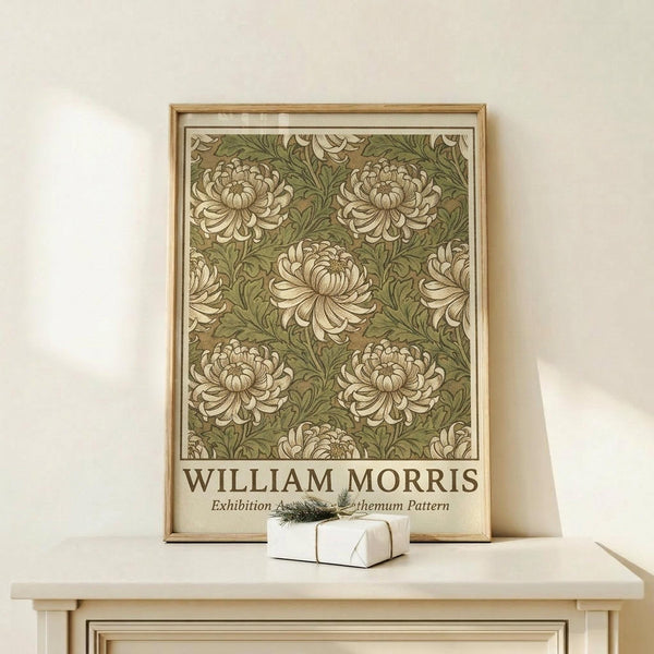May include: Framed botanical poster featuring repeating chrysanthemum flowers in cream and sage green colors, displayed on light wood shelf against white wall. Small white gift box with twine and evergreen sprig sits in front of the natural wood frame.