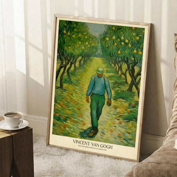 May include: Framed Van Gogh poster print leaning against white wall on textured cream rug. Artwork shows figure in blue shirt and green pants walking down path through orchard with fruit trees and fallen oranges scattered on ground. Swirling brushstroke style in vibrant greens and yellows. Natural wood frame with cream matting. Coffee cup on wooden side table nearby, soft natural lighting creating shadows.