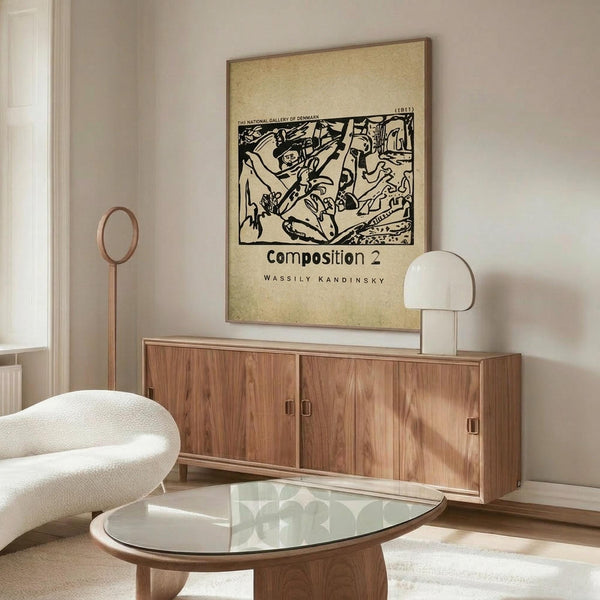 May include: Modern living room interior featuring a framed vintage art poster on beige wall above wooden sideboard. Abstract black line drawing on cream background shows dynamic figures and forms. Room styled with white curved chair, glass oval coffee table, white table lamp, and copper floor lamp on polished floors.